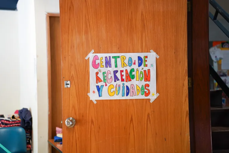 Un cartel realizado por niñas y niños pegado con cinta a una puerta. El cartel indica "Centro de Recreación y Cuidados".